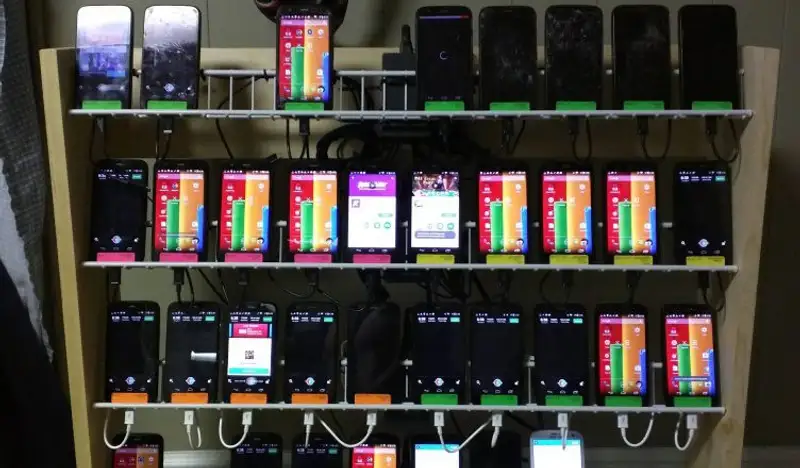 Physical phone farm setup with multiple smartphones on racks